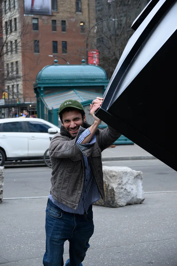 On location holding a flag against a car and a New York street