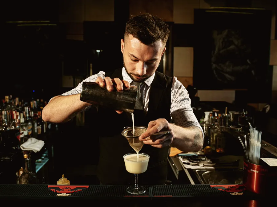 A bartender finishing a drink at a cocktail bar