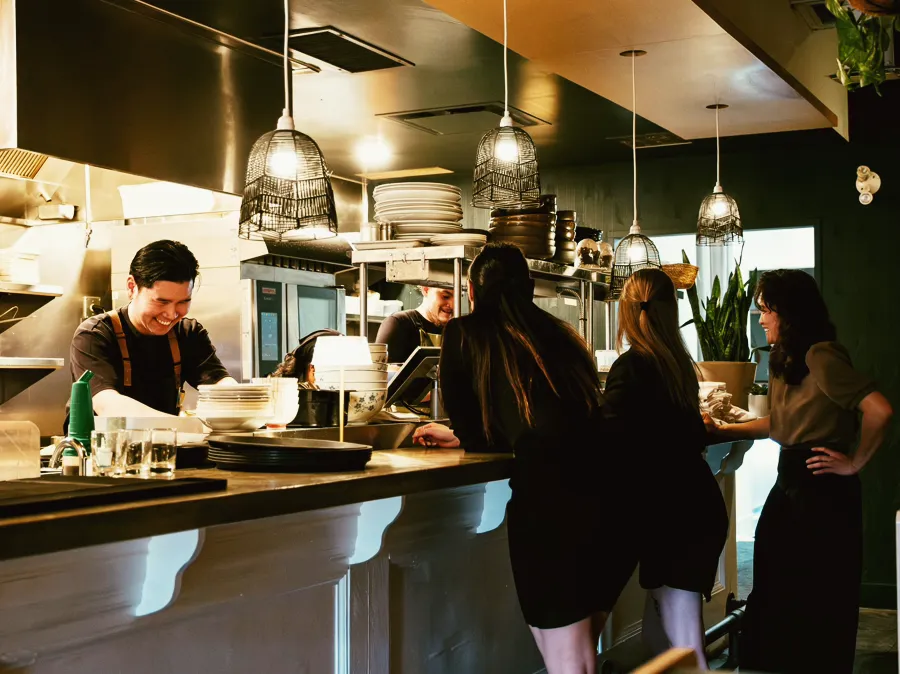 A chef plating at the pass of a small restaurant