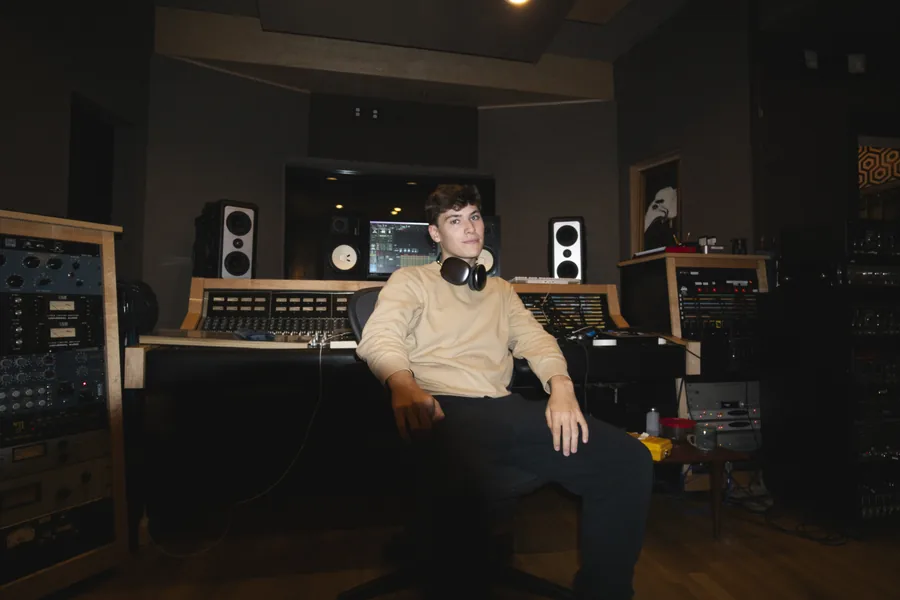 Seated at the mixing desk, headphones around his neck